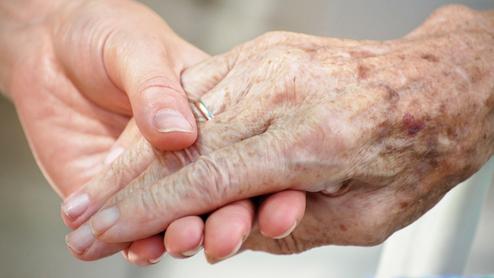 Nahaufnahme zweier Hände, eine ältere und eine jüngere, die sich liebevoll halten.